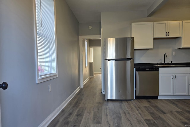 kitchen with appliances with stainless steel finishes, dark hardwood / wood-style floors, white cabinetry, and sink