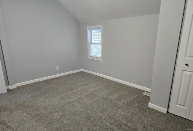 carpeted empty room with vaulted ceiling