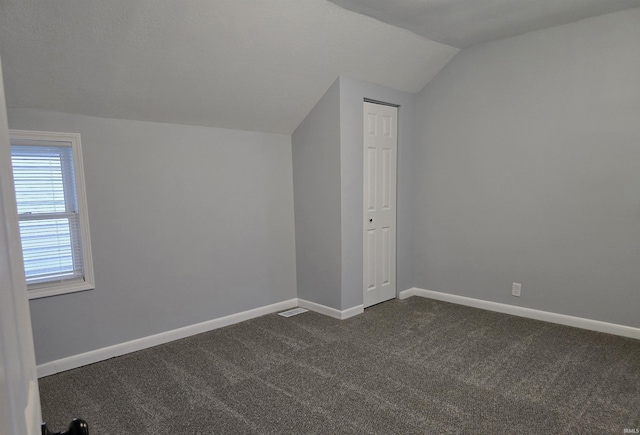 additional living space with lofted ceiling and dark colored carpet