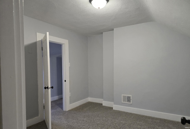 carpeted spare room featuring a textured ceiling and vaulted ceiling