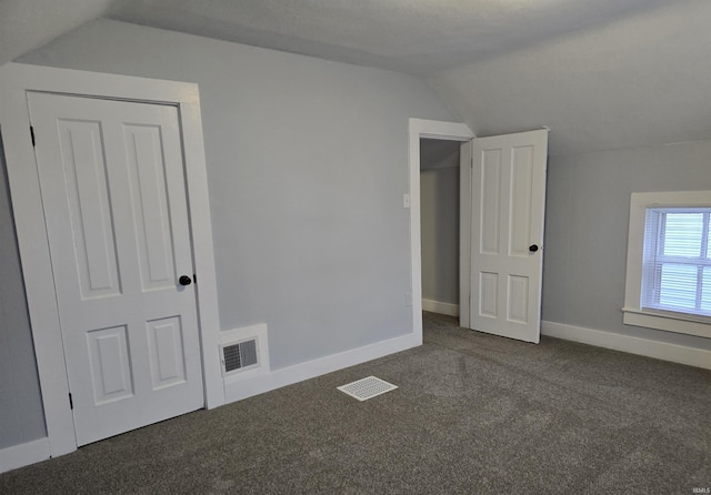 bonus room with dark colored carpet and vaulted ceiling