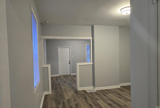 corridor with dark hardwood / wood-style flooring and a textured ceiling