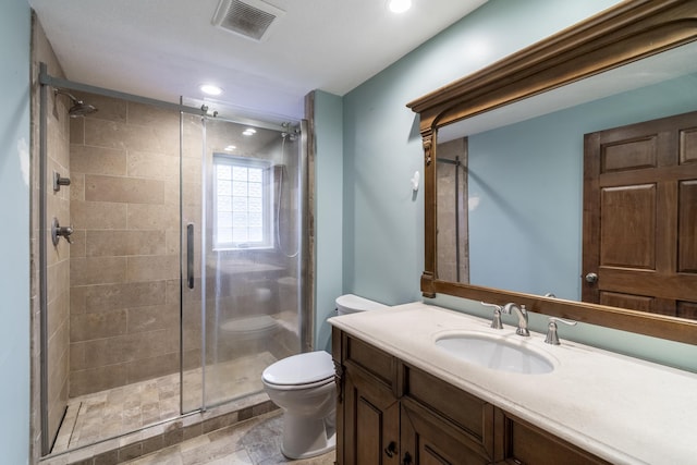 bathroom featuring vanity, toilet, and a shower with door