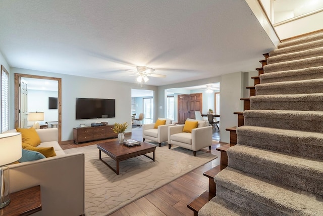 living room featuring ceiling fan, a textured ceiling, and hardwood / wood-style flooring