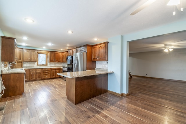 kitchen with kitchen peninsula, decorative backsplash, hardwood / wood-style floors, and stainless steel appliances