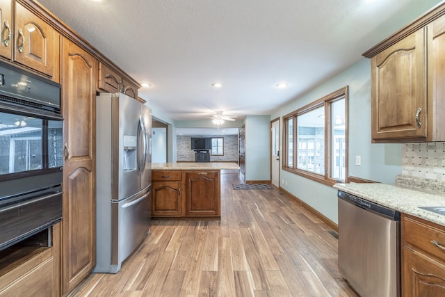 kitchen with ceiling fan, stainless steel appliances, light hardwood / wood-style flooring, kitchen peninsula, and decorative backsplash