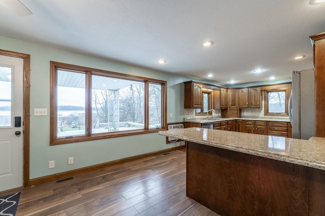 kitchen with light stone countertops, a textured ceiling, stainless steel appliances, sink, and dark hardwood / wood-style floors