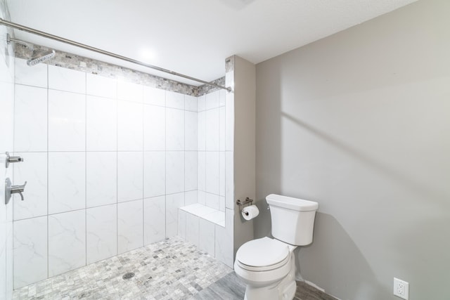 bathroom featuring tiled shower, hardwood / wood-style floors, and toilet