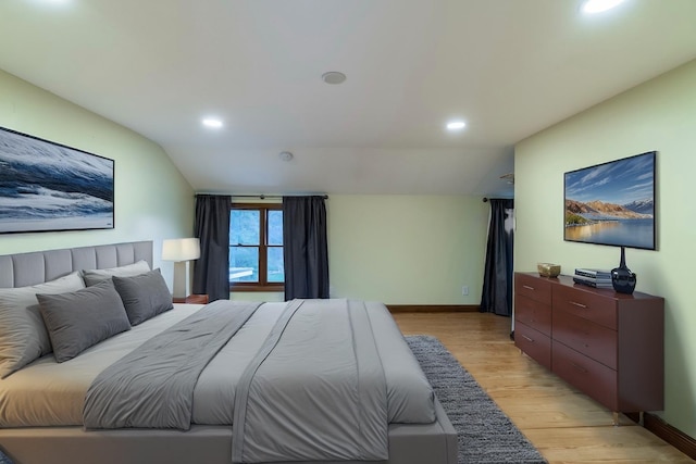 bedroom featuring light wood-type flooring and vaulted ceiling