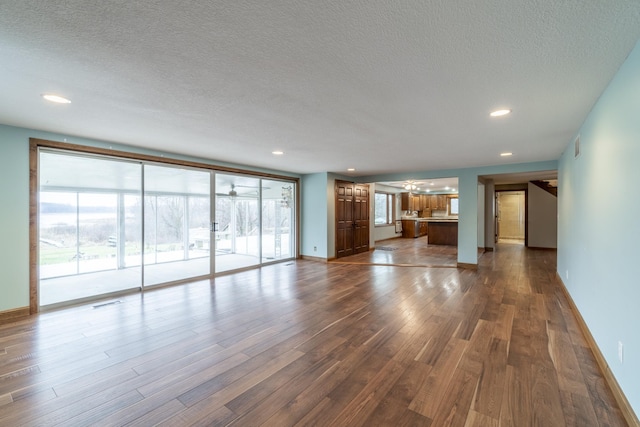 unfurnished living room with a textured ceiling and dark hardwood / wood-style floors