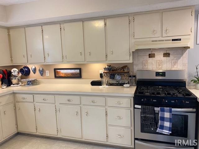 kitchen featuring white cabinets, backsplash, and stainless steel gas range oven