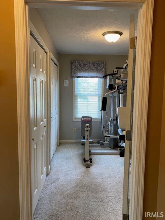 exercise area with light carpet and a textured ceiling