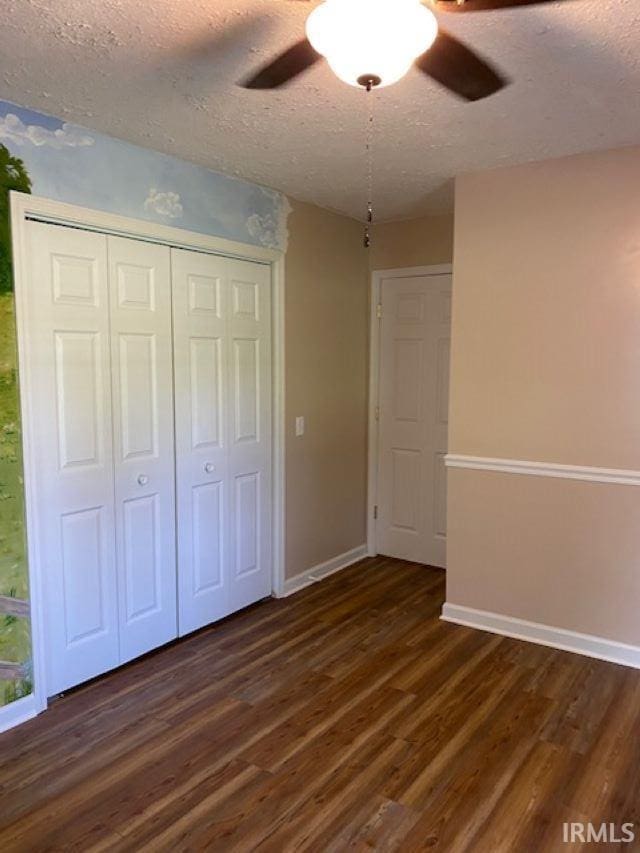 unfurnished bedroom with dark hardwood / wood-style floors, ceiling fan, and a textured ceiling