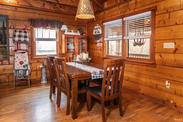 dining room featuring wood-type flooring, plenty of natural light, and wooden walls