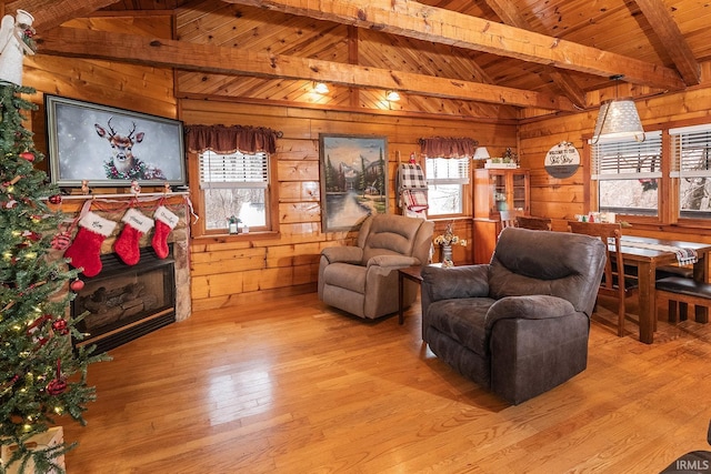 living room featuring lofted ceiling with beams, wood walls, wooden ceiling, and light wood-type flooring