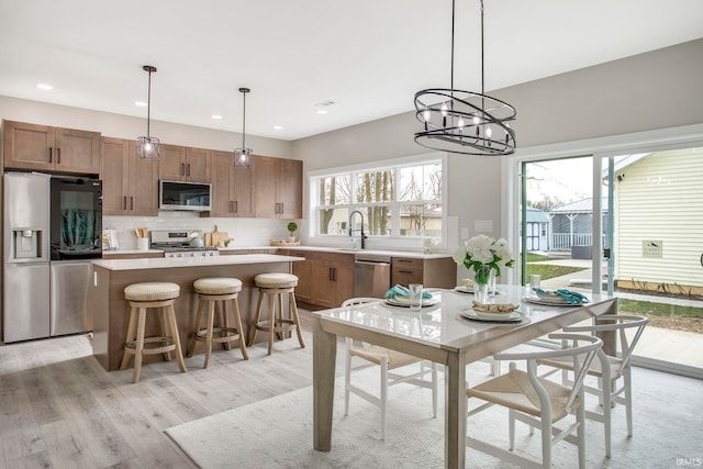 kitchen with hanging light fixtures, light hardwood / wood-style flooring, a center island, and stainless steel appliances