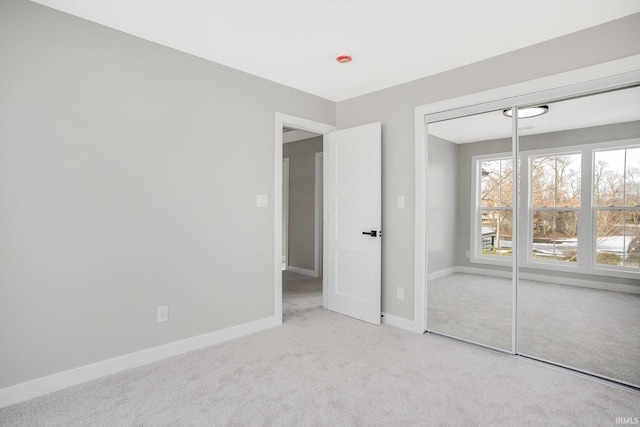 unfurnished bedroom featuring light carpet and a closet