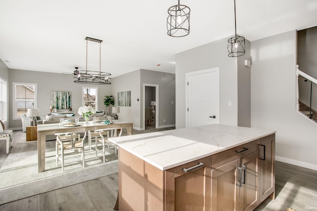 kitchen with light stone countertops, a kitchen island, pendant lighting, and hardwood / wood-style flooring