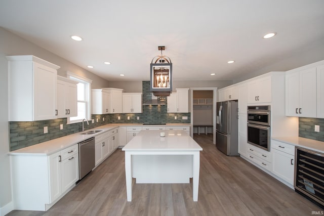 kitchen featuring white cabinetry, hardwood / wood-style floors, hanging light fixtures, and appliances with stainless steel finishes