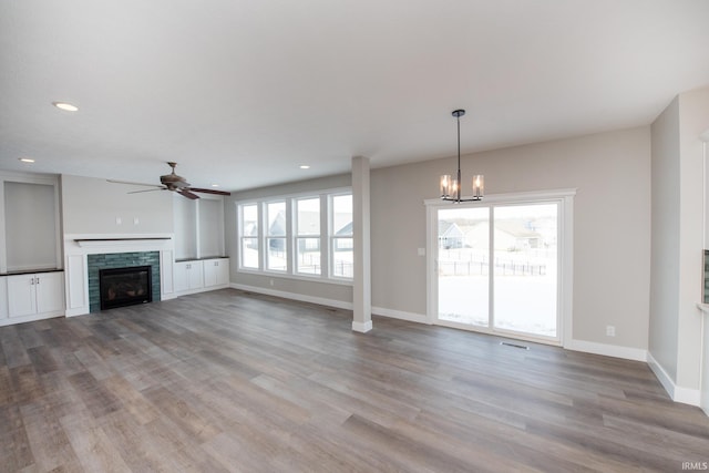 unfurnished living room featuring light hardwood / wood-style floors, a stone fireplace, and a healthy amount of sunlight