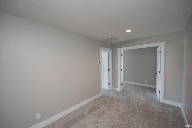 empty room with light carpet and a textured ceiling