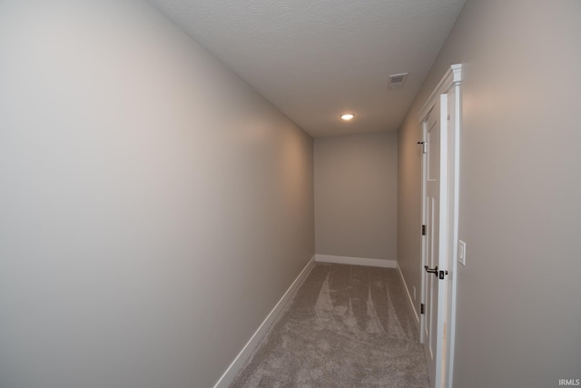 hallway with light carpet and a textured ceiling