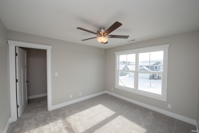 empty room featuring ceiling fan and light carpet