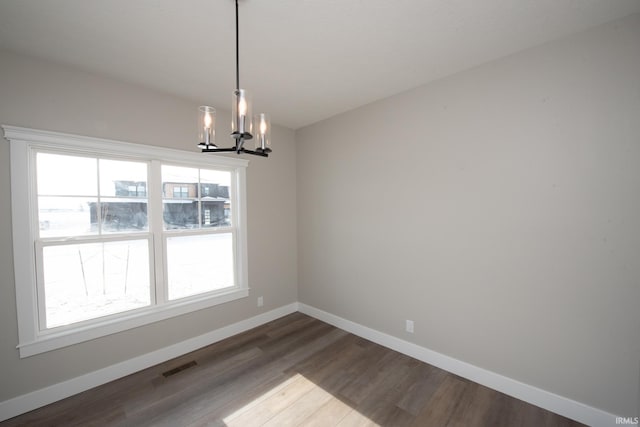 unfurnished dining area with a healthy amount of sunlight, dark hardwood / wood-style flooring, and a chandelier