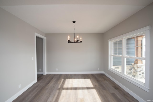 unfurnished dining area featuring an inviting chandelier and dark wood-type flooring