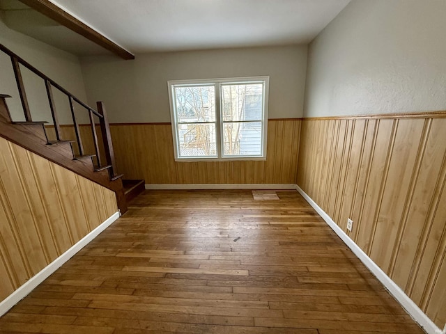 spare room with dark hardwood / wood-style flooring and wood walls