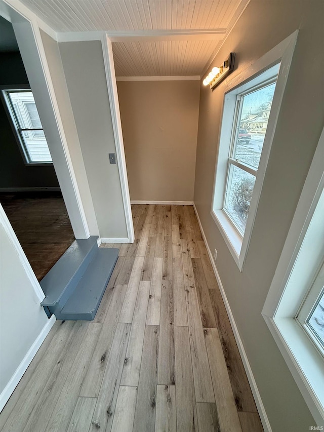 corridor with light hardwood / wood-style floors, ornamental molding, and wood ceiling