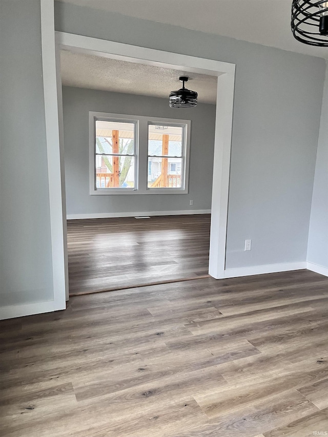 empty room with a textured ceiling and light hardwood / wood-style flooring