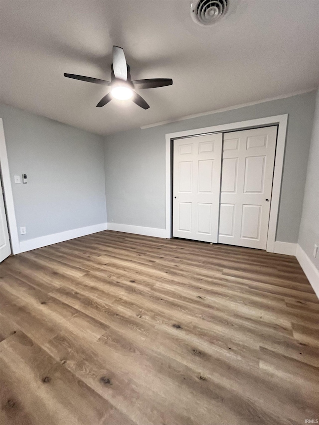 unfurnished bedroom featuring a closet, ceiling fan, hardwood / wood-style floors, and ornamental molding