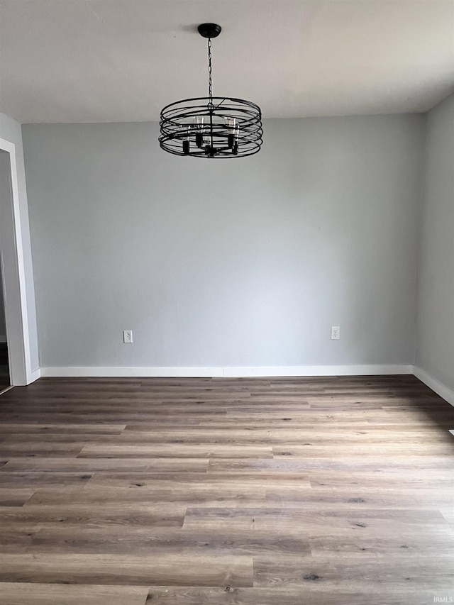 unfurnished dining area with hardwood / wood-style floors and a notable chandelier