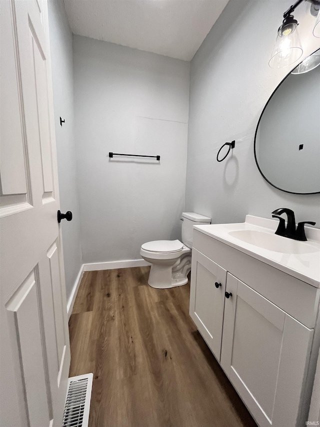 bathroom with hardwood / wood-style flooring, vanity, and toilet