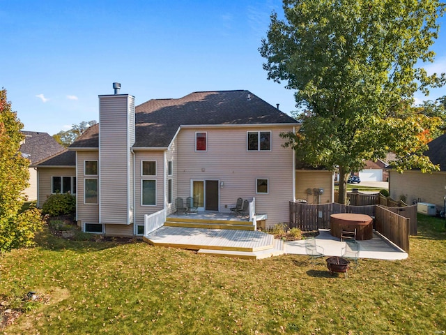 rear view of property with a lawn, an outdoor fire pit, and a wooden deck