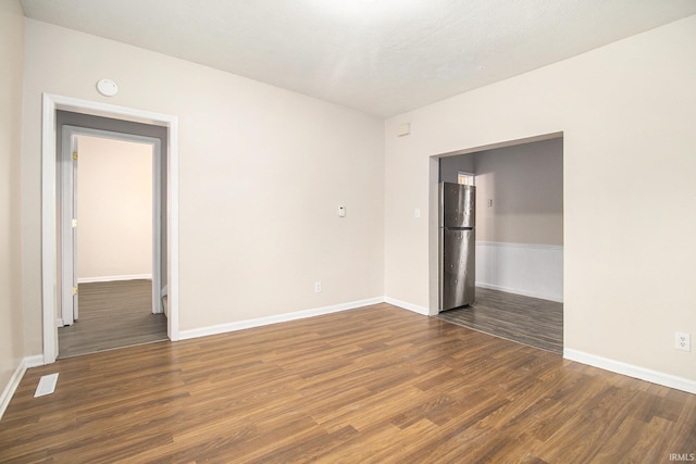 spare room featuring dark hardwood / wood-style flooring and a textured ceiling