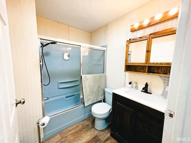 full bathroom featuring hardwood / wood-style floors, vanity, toilet, and combined bath / shower with glass door