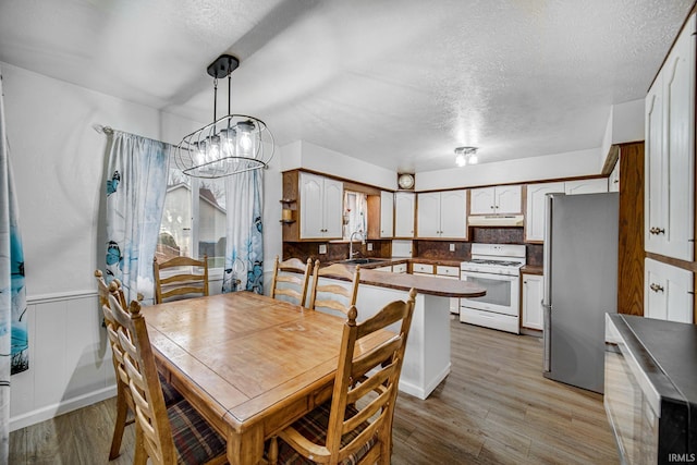 dining room featuring sink, wood-type flooring, and a textured ceiling