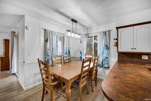 dining room with a chandelier, light hardwood / wood-style floors, and a textured ceiling