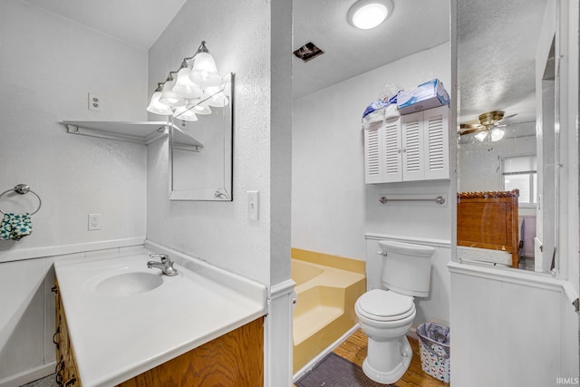 bathroom featuring ceiling fan, vanity, toilet, and a bathtub