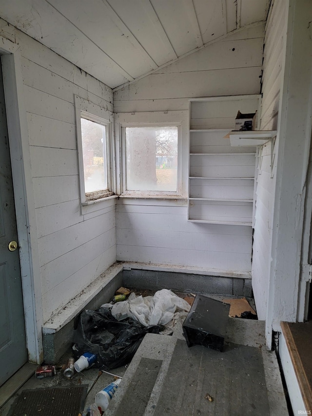 unfurnished bedroom with wood walls and lofted ceiling