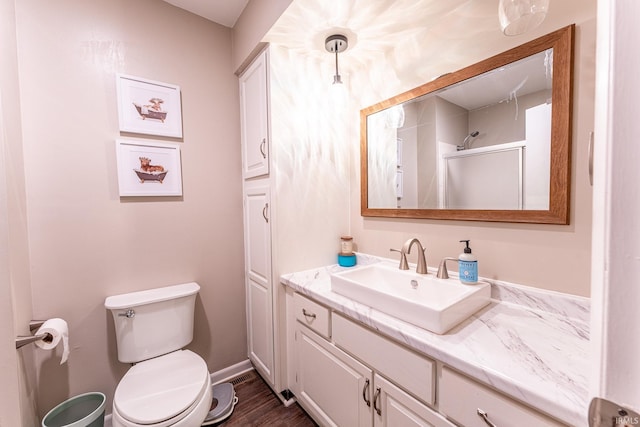 bathroom with hardwood / wood-style floors, vanity, toilet, and a shower with shower door