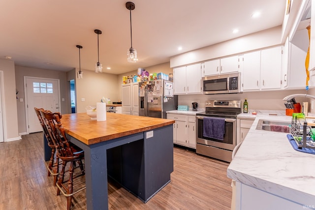 kitchen with white cabinetry, pendant lighting, stainless steel appliances, and sink