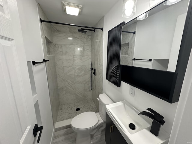 bathroom with vanity, toilet, and a tile shower