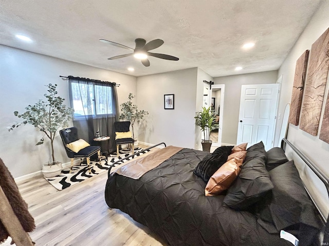 bedroom with ceiling fan, light wood-type flooring, and a textured ceiling