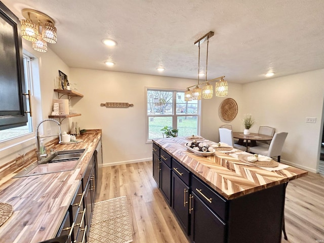 kitchen featuring pendant lighting, a center island, light hardwood / wood-style flooring, a kitchen bar, and butcher block counters