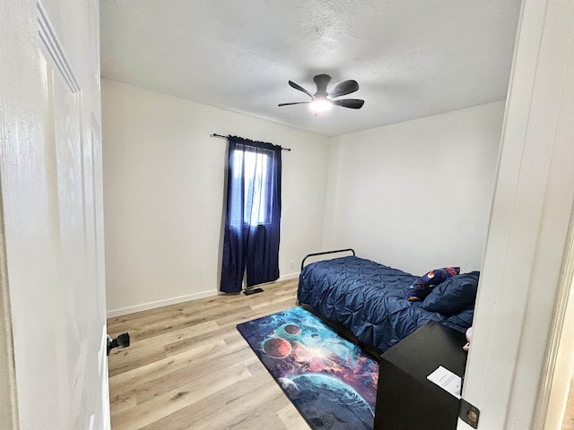 bedroom featuring hardwood / wood-style flooring, ceiling fan, and a textured ceiling