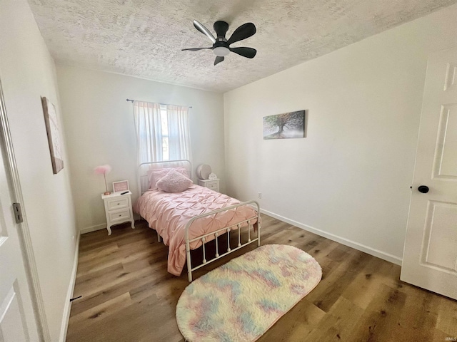 bedroom with ceiling fan, hardwood / wood-style floors, and a textured ceiling