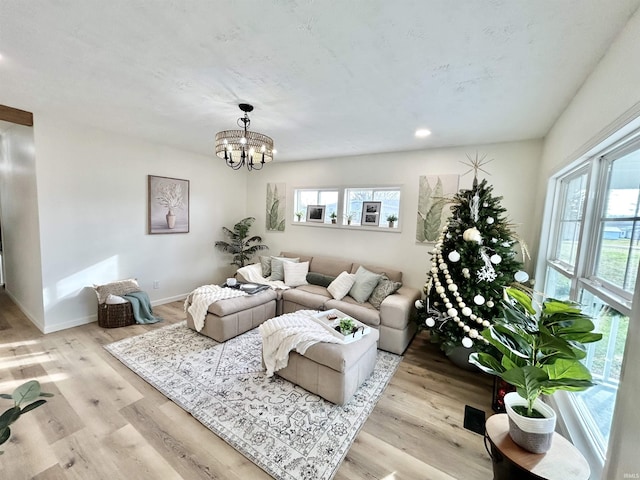 living room featuring a wealth of natural light, an inviting chandelier, and light wood-type flooring